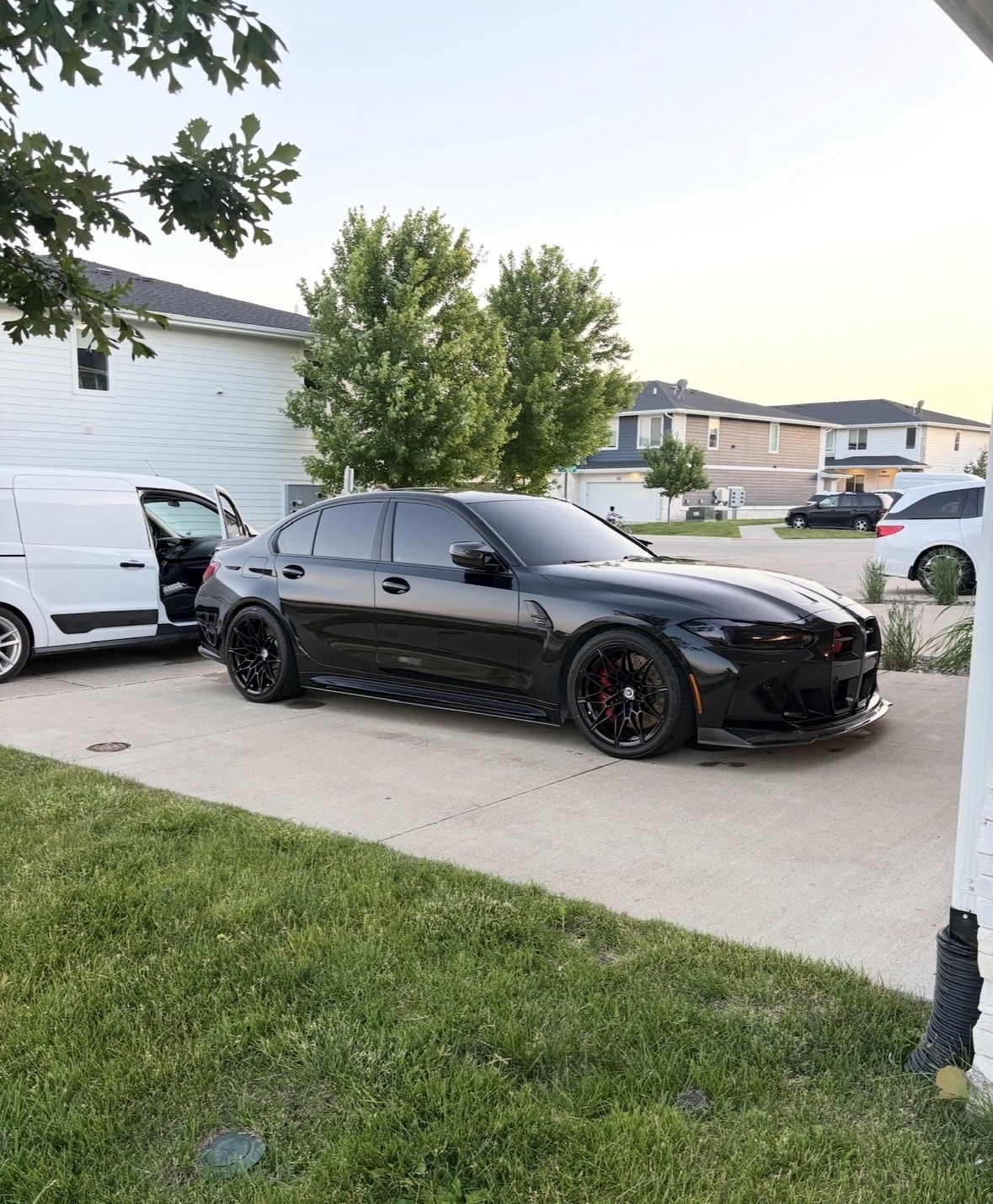 Black BMW M3 detailed in a driveway beside the Noble service van